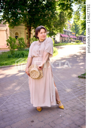 plus size woman in peach fuzz dress with hat having fun on morning city streets plus size woman in peach fuzz dress with hat having fun on morning city streets 114627781