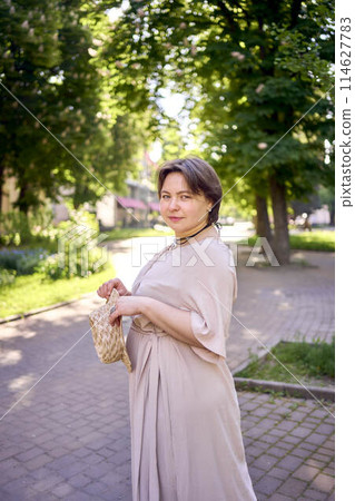 plus size woman in peach fuzz dress with hat having fun on morning city streets plus size woman in peach fuzz dress with hat having fun on morning city streets 114627783