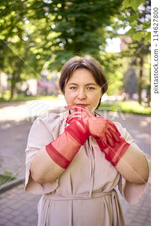 plus size woman in peach fuzz dress and red translucent gloves dancing in the morning city streets 114627800