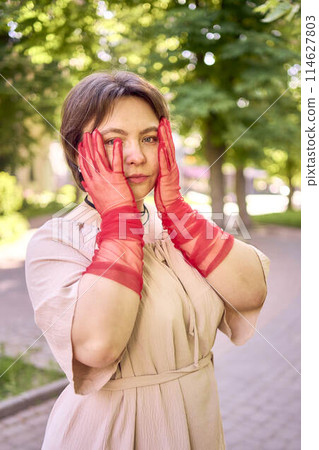 plus size woman in peach fuzz dress and red translucent gloves dancing in the morning city streets plus size woman in peach fuzz dress and red translucent gloves dancing in the morning city streets 114627803