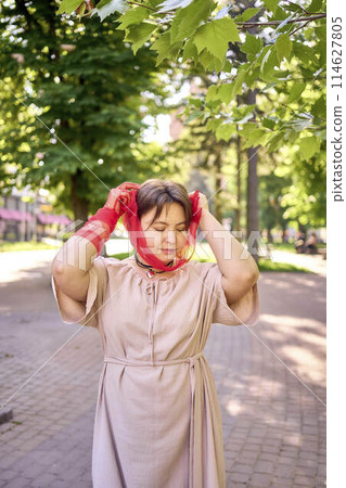 plus size woman in peach fuzz dress and red translucent gloves dancing in the morning city streets 114627805