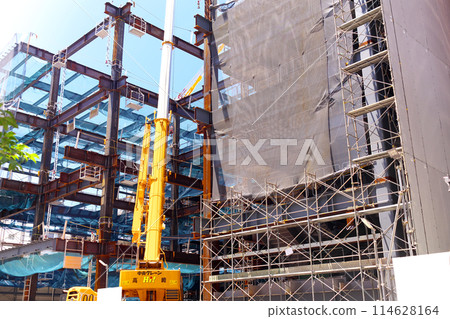 A crane working on steel frames during a building construction project 114628164