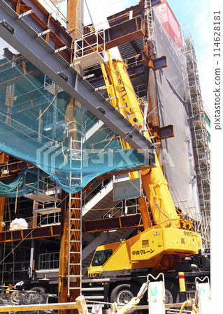 A crane working on steel frames during a building construction project A crane working on steel frames during a building construction project 114628181