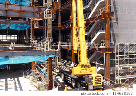 A crane working on steel frames during a building construction project A crane working on steel frames during a building construction project 114628192