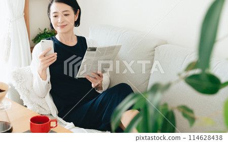 看智慧型手機和英文報紙的中年婦女 114628438
