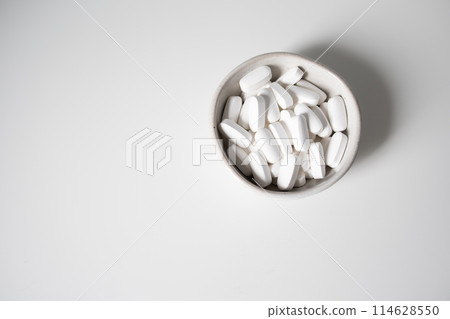 White pills in small bowl on a white background White pills in small bowl on a white background 114628550