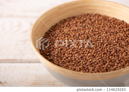 buckwheat groats in a wooden plate on a wooden background close up 114629265