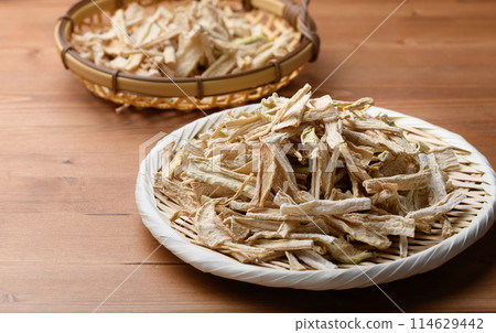 Dried daikon radish slices served on a colander (wood grain background) Dried daikon radish slices served on a colander (wood grain background) 114629442