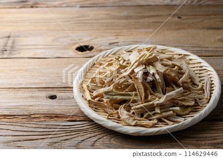 Dried daikon radish slices served on a colander (against old wood background) Dried daikon radish slices served on a colander (against old wood background) 114629446