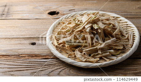 Dried daikon radish slices served on a colander (against old wood background) 114629449
