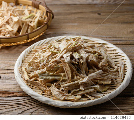 Dried daikon radish slices served on a colander (against old wood background) Dried daikon radish slices served on a colander (against old wood background) 114629453