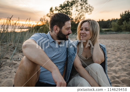 woman and man spending romantic time together on beach on sunset 114629458