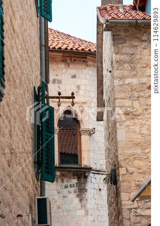Beautiful window in Gothic building. View among buildings in old Mediterranean city. Vertical orientation Beautiful window in Gothic building. View among buildings in old Mediterranean city. Vertical orientation 114629893