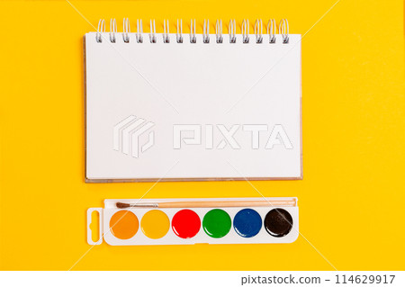 Watercolors with a brush and copybook on a yellow background. Flat lay. Mock up. Copy space. The concept of creativity Watercolors with a brush and copybook on a yellow background. Flat lay. Mock up. Copy space. The concept of creativity 114629917