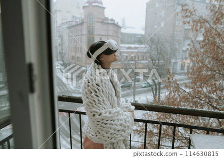 Engrossed in virtual reality, a girl stands against the backdrop of the winter city. Engrossed in virtual reality, a girl stands against the backdrop of the winter city. 114630815