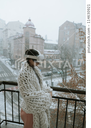 A beautiful girl in virtual reality glasses against the backdrop of a winter cityscape. A beautiful girl in virtual reality glasses against the backdrop of a winter cityscape. 114630921