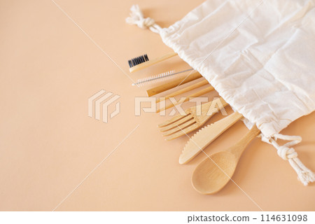 Eco friendly bag and bamboo cutlery set with toothbrush on beige background for green life and zero waste concept. Top view 114631098