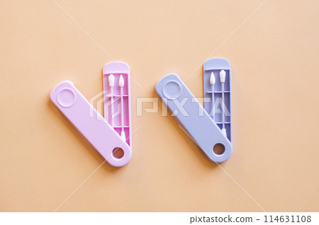 Reusable silicone ear sticks in colored cases with a top view on a beige background. An alternative to disposable cotton swabs. Reduce costs and save money. Reusable silicone ear sticks in colored cases with a top view on a beige background. An alternative to disposable cotton swabs. Reduce costs and save money. 114631108