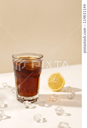 glass of alcoholic drink on the table with ice cubes and lemon. long shadow. party and cocktail concept. rum and cola 114631144