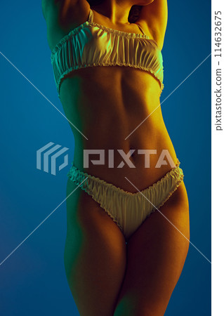 Cropped image of perfect female body, slim waist and slender legs, in elegant underwear against cyan background in neon light 114632675