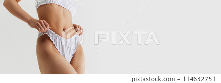 Cropped image of female body, slim waist. Model posing in tender white lingerie isolated on grey studio background Cropped image of female body, slim waist. Model posing in tender white lingerie isolated on grey studio background 114632751