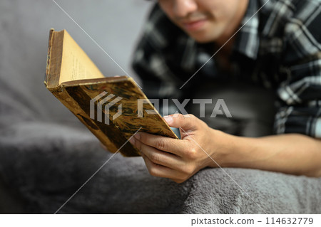 Relaxed man reading on couch spending free time on the weekend at home Relaxed man reading on couch spending free time on the weekend at home 114632779