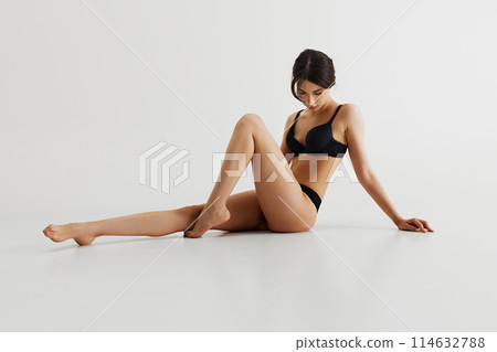Elegant and sensual, beautiful young girl with slim, perfect body posing in black lingerie isolated on grey studio background Elegant and sensual, beautiful young girl with slim, perfect body posing in black lingerie isolated on grey studio background 114632788