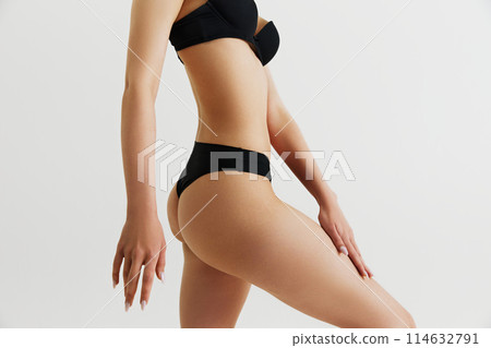 Anti-cellulite message care. Cropped image of female body in inner wear, slender smooth legs and buttocks. Model isolated on grey studio background 114632791