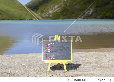 YTD year to date symbol. Concept words YTD year to date on beautiful yellow blackboard. Beautiful mountain lake background. Business YTD year to date concept. Copy space. 114633084