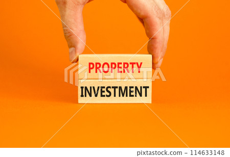 Property investment symbol. Concept words Property investment on beautiful wooden block. Beautiful orange paper background. Businessman hand. Business Property investment concept. Copy space. Property investment symbol. Concept words Property investment on beautiful wooden block. Beautiful orange paper background. Businessman hand. Business Property investment concept. Copy space. 114633148