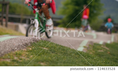Blurred little girl rides a bike along the hilly pumptrack Blurred little girl rides a bike along the hilly pumptrack 114633528