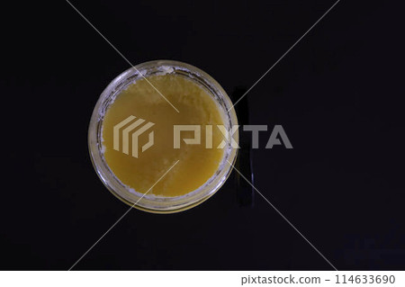 butter ghee in a transparent jar with homemade bread on a black background butter ghee in a transparent jar with homemade bread on a black background 114633690
