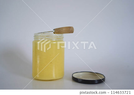 butter ghee in a transparent jar with homemade bread on a white background butter ghee in a transparent jar with homemade bread on a white background 114633721