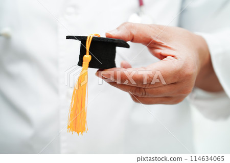 Asian woman doctor holding graduation hat in hospital, Medical education concept. Asian woman doctor holding graduation hat in hospital, Medical education concept. 114634065