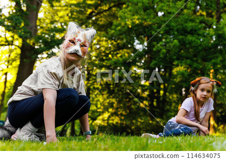 Cute young little kid girl wear cat furry mask enjoy have fun playing outdoors in forest street park. Children therian wild animal character trendy fan culture. Teenager social expression hobby Cute young little kid girl wear cat furry mask enjoy have fun playing outdoors in forest street park. Children therian wild animal character trendy fan culture. Teenager social expression hobby 114634075