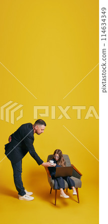 Father-Daughter Work Session. Father and daughter in formal attire working together. Dad helps daughter against sunny-yellow background. Father-Daughter Work Session. Father and daughter in formal attire working together. Dad helps daughter against sunny-yellow background. 114634349
