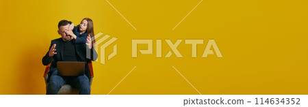 Banner. Father working online and little child want to play with him against sunny-yellow background. Parenthood. 114634352