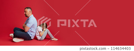 Banner. Father and daughter sit back-to-back, reflecting a moment of conflict or disagreement against vibrant red background. Banner. Father and daughter sit back-to-back, reflecting a moment of conflict or disagreement against vibrant red background. 114634403