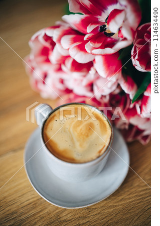 Spring tulips and cup of coffee on wooden table Spring tulips and cup of coffee on wooden table 114634490