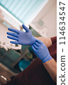 Doctor puts on blue rubber gloves 114634547
