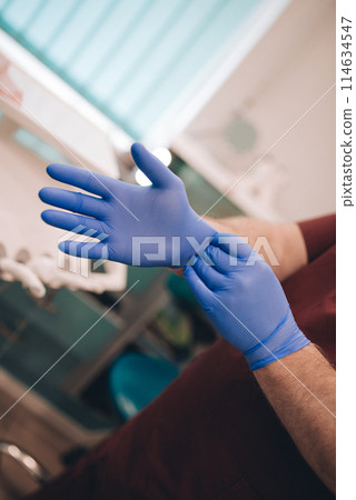 Doctor puts on blue rubber gloves Doctor puts on blue rubber gloves 114634547