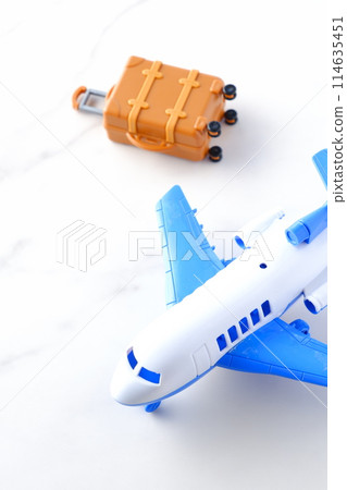 An image of a plane waiting to take off and a suitcase (carry-on suitcase) about to depart for a trip 114635451