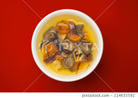 Beef stew with broth, soup with meat and vegetable on red background with copy space, top view 114635592