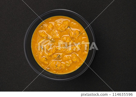 Spicy asian cream soup in black bowl on black background with copy space, top view, full depth of field Spicy asian cream soup in black bowl on black background with copy space, top view, full depth of field 114635596