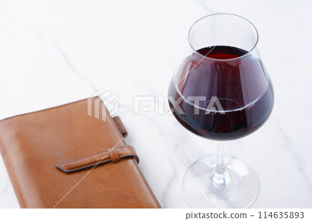brown leather organizer and glass of red wine brown leather organizer and glass of red wine 114635893