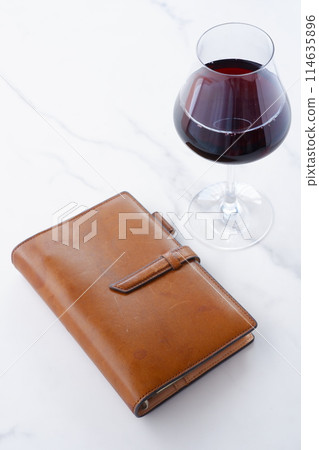 brown leather organizer and glass of red wine brown leather organizer and glass of red wine 114635896