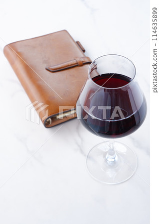 brown leather organizer and glass of red wine brown leather organizer and glass of red wine 114635899