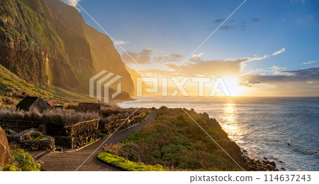 Volcanic rock cliffs Achadas da Cruz in backlit sunlight. Waves of the Atlantic Ocean. Beautiful sunset seascape of the resort island of Madeira, Portugal 114637243