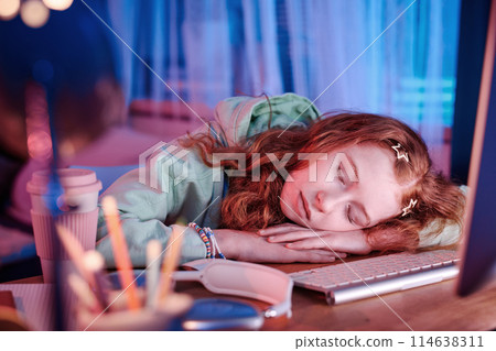 Portrait of tired teen girl with long red hair falling asleep with head on desk in her room at home, copy space Portrait of tired teen girl with long red hair falling asleep with head on desk in her room at home, copy space 114638311