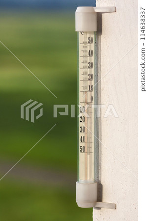 Thermometer celsius showing warm temperature on blurred green background. Weather forecast concept. 114638337